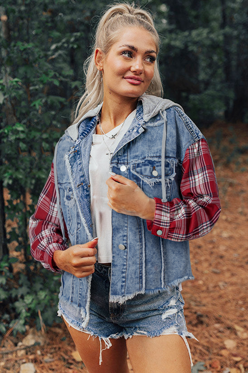 Blond woman wearing denim jacket with red and white plaid sleeves, flap pockets, hood, and button up closure. Front open view