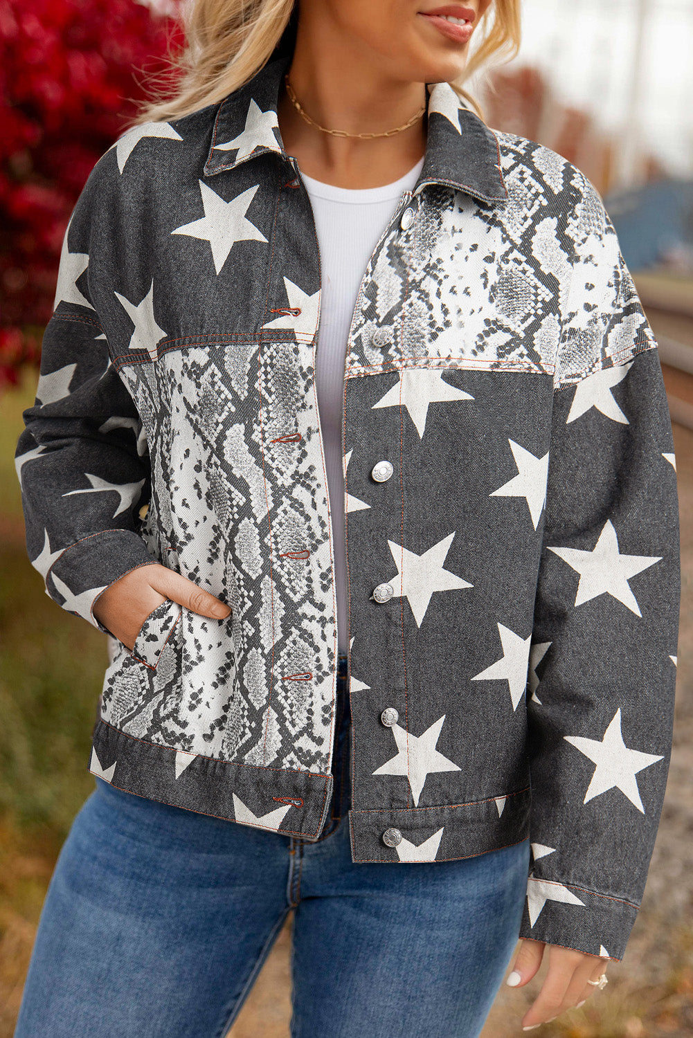 blond woman wearing black denim jacket printed with snakeskin and stars. front close up view