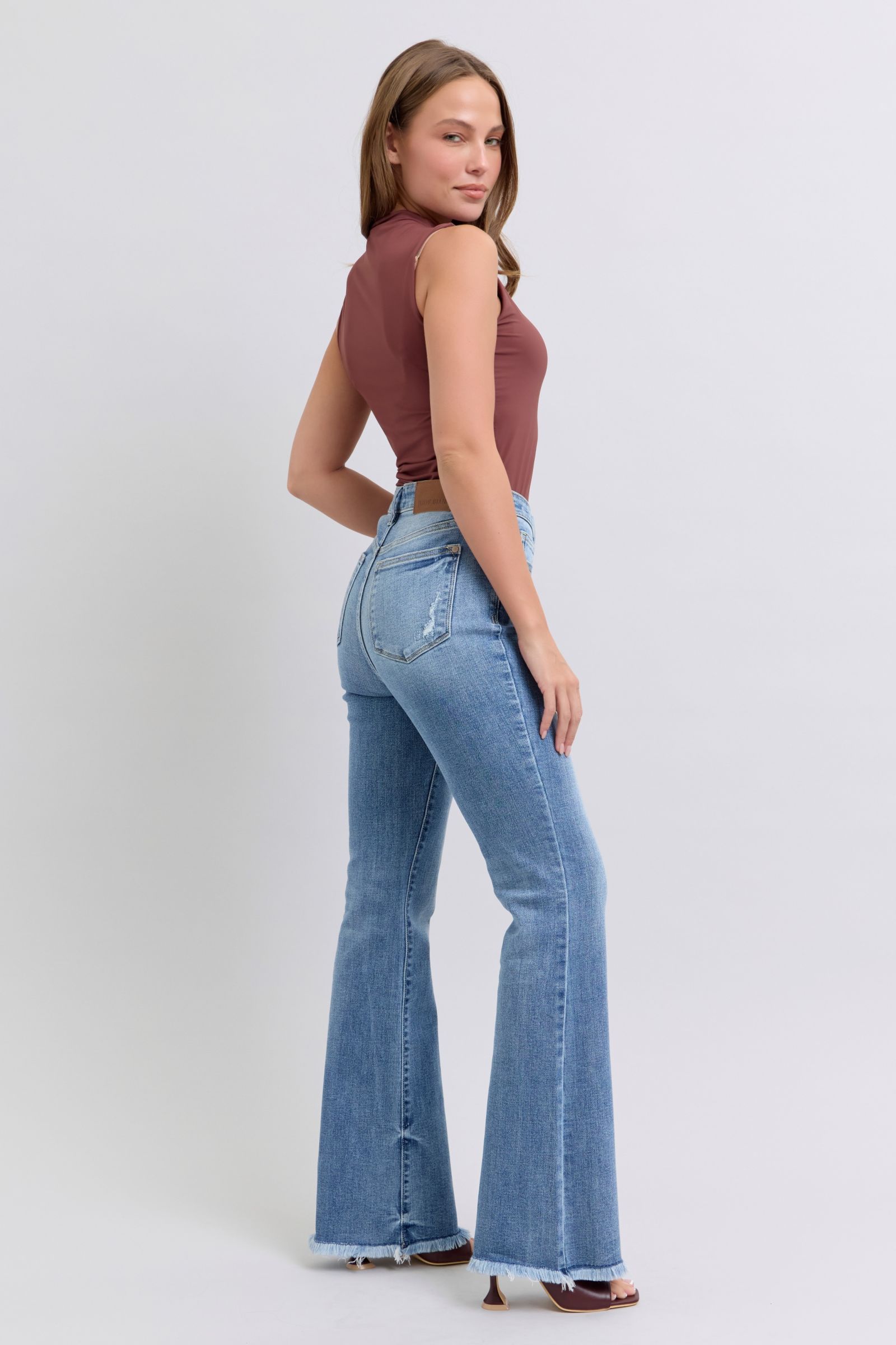 Judy Blue Raw hem high rise bootcut jeans are a trendy and stylish denim option for a fashionable look. These jeans feature a high-rise waist that sits above the natural waistline, elongating the legs and providing a flattering silhouette. The bootcut style flares out slightly from the knee down, creating a balanced and vintage-inspired look. The raw hem detail at the bottom adds a modern and edgy touch to the jeans, giving them a unique and on-trend appearance.  Back right view