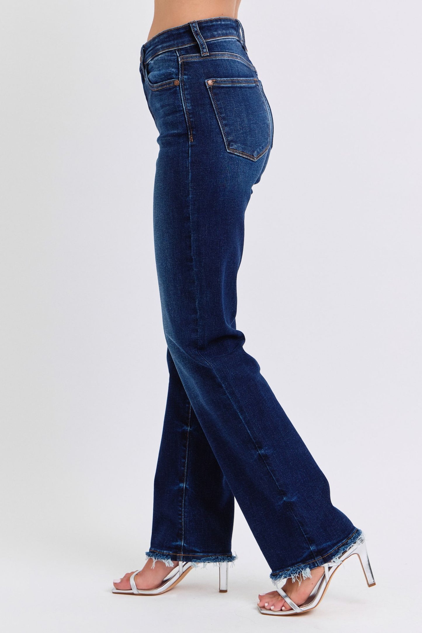 Judy Blue Raw Hem Straight Leg Jeans are a versatile and timeless addition to your wardrobe. The raw hem adds a touch of edge, while the straight leg style offers a flattering silhouette. Perfect for both casual and dressy looks, these jeans are a must-have for any fashion-forward individual. Left side view