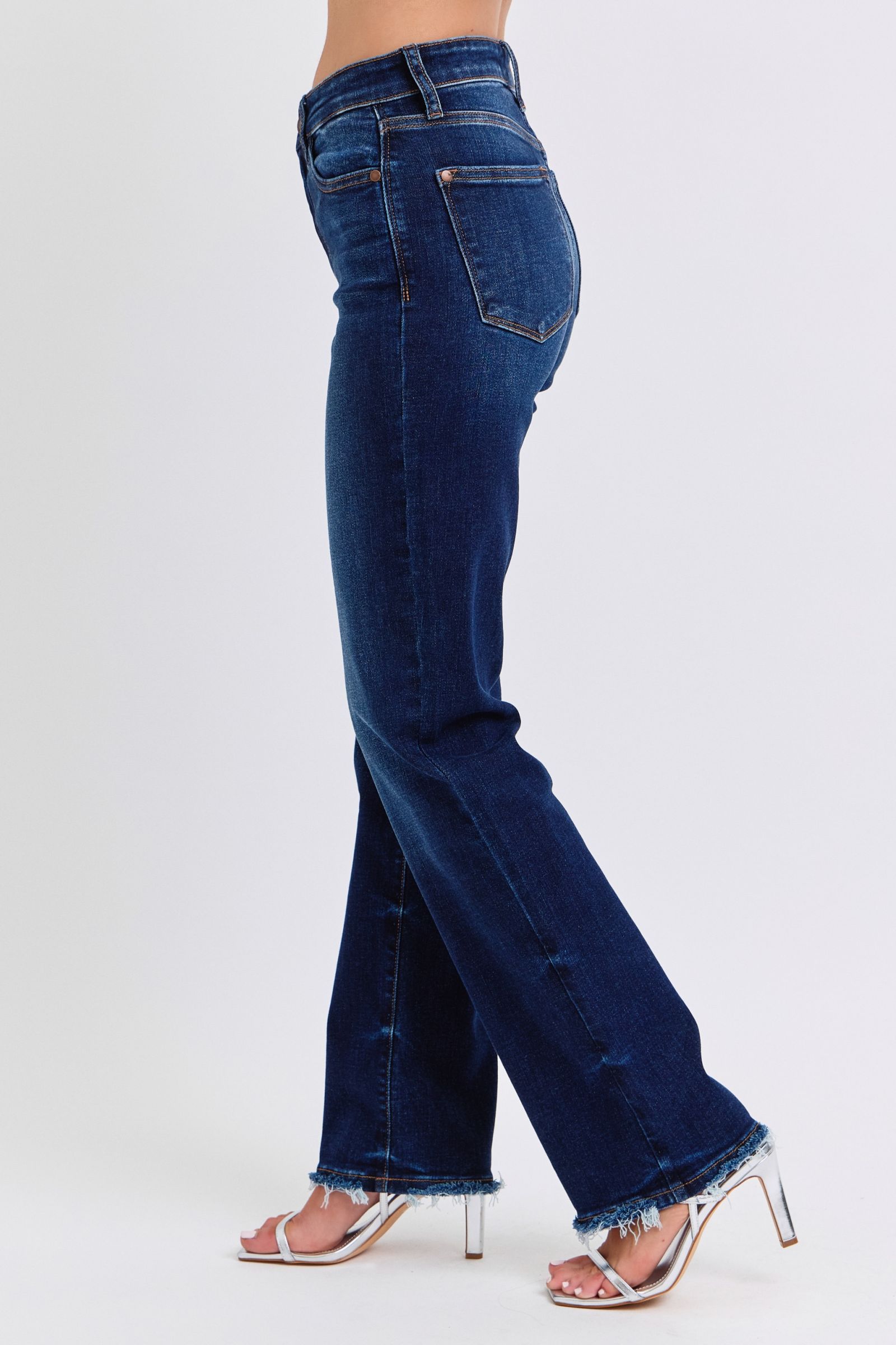 Judy Blue Raw Hem Straight Leg Jeans are a versatile and timeless addition to your wardrobe. The raw hem adds a touch of edge, while the straight leg style offers a flattering silhouette. Perfect for both casual and dressy looks, these jeans are a must-have for any fashion-forward individual. Left side view