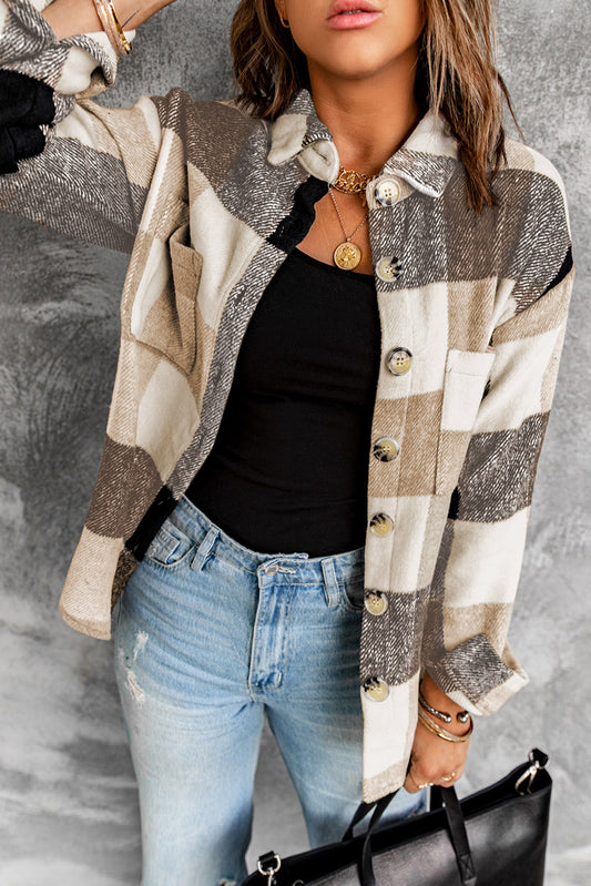 Brown haired woman wearing khaki and black plaid flannel with large button closure and pockets. Front open view
