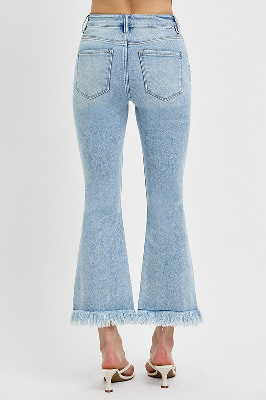 Risen Raw hem distressed cropped flare jeans offer a stylish and edgy twist to your denim collection. The cropped length hits above the ankle, making them perfect for showcasing your footwear. The flare silhouette adds a retro and fun vibe to the jeans, while the distressed detailing gives them a cool and worn-in look. The raw hem finish adds a touch of casual and laid-back charm to the jeans, making them ideal for a relaxed yet trendy outfit. Back view