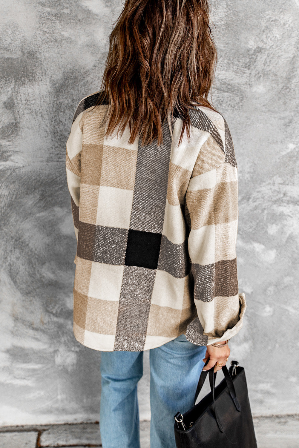 Brown haired woman wearing khaki and black plaid flannel with large button closure and pockets. back view