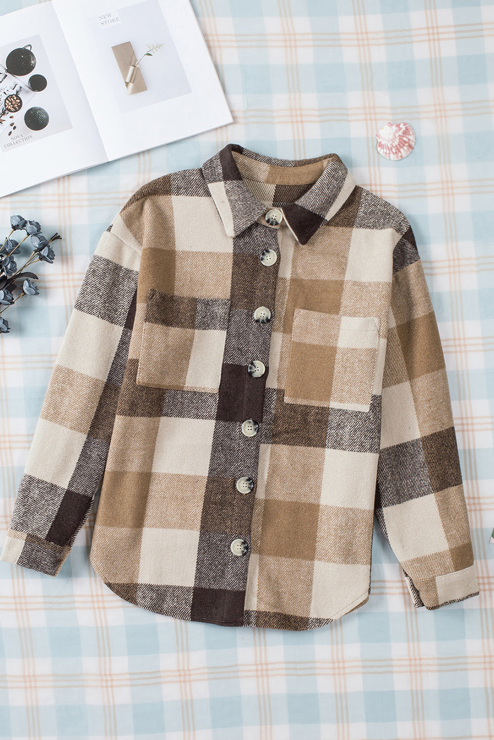 Brown haired woman wearing khaki and black plaid flannel with large button closure and pockets. Front flat lay view