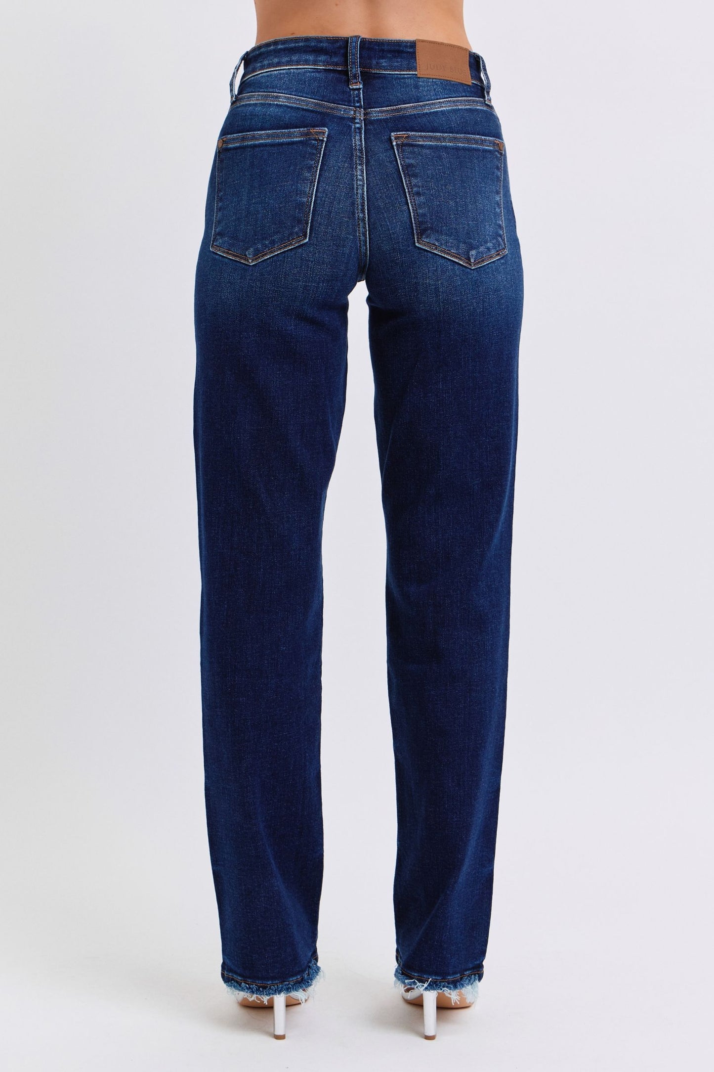 Judy Blue Raw Hem Straight Leg Jeans are a versatile and timeless addition to your wardrobe. The raw hem adds a touch of edge, while the straight leg style offers a flattering silhouette. Perfect for both casual and dressy looks, these jeans are a must-have for any fashion-forward individual. Back view