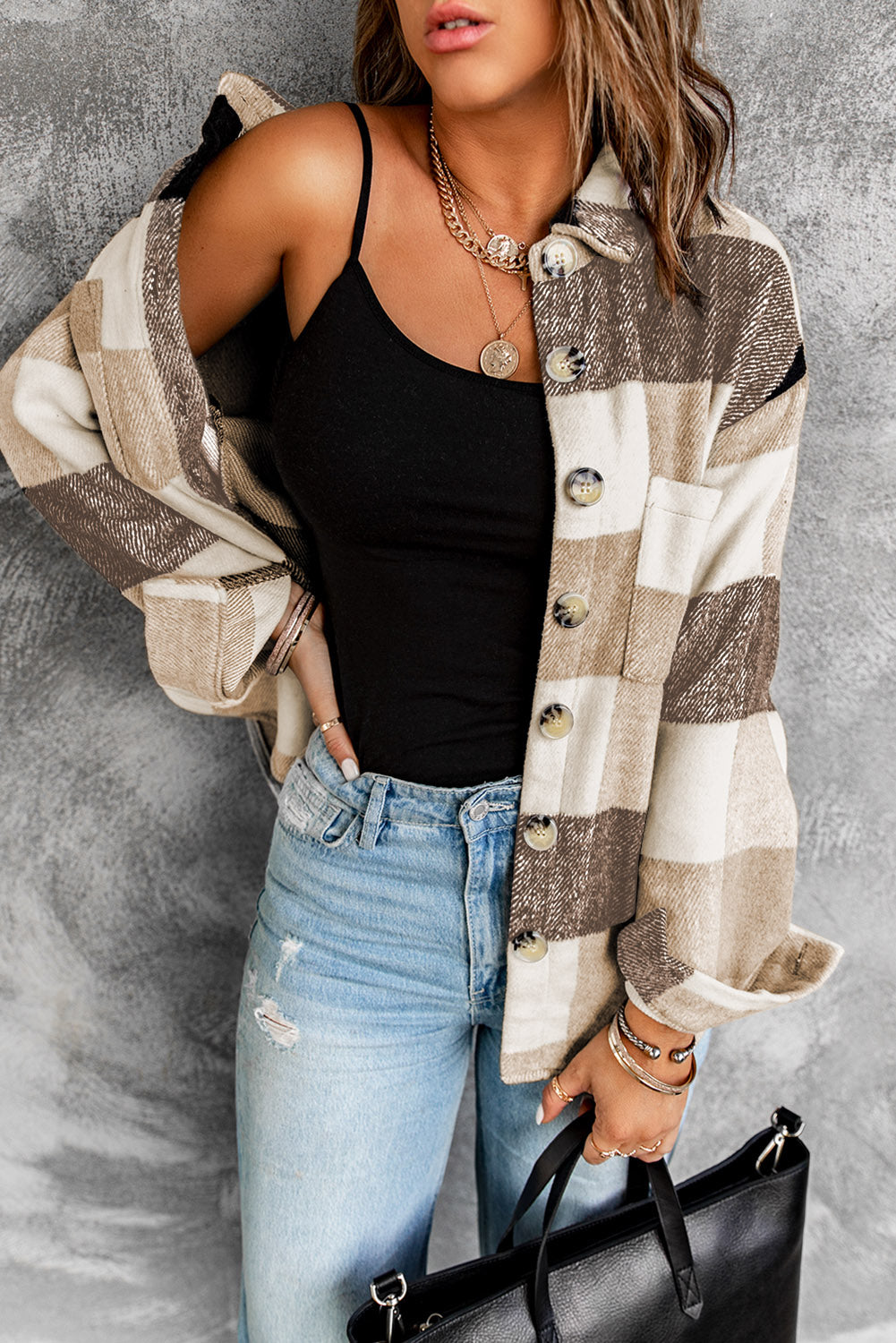 Brown haired woman wearing khaki and black plaid flannel with large button closure and pockets. Front off-shoulder view