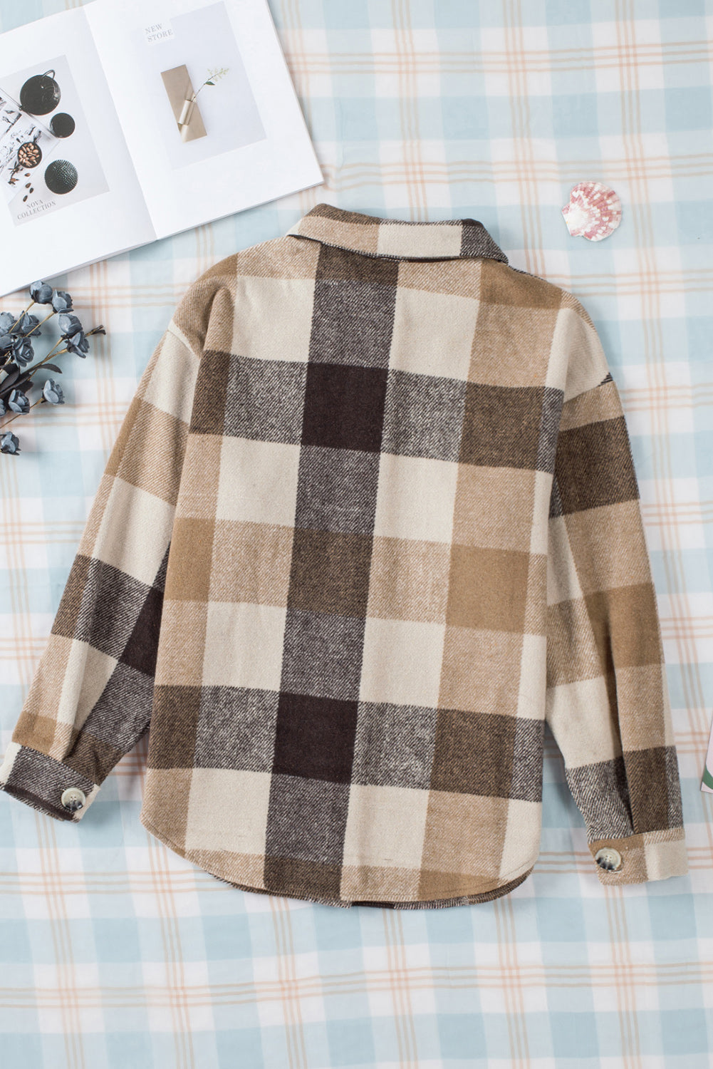 Brown haired woman wearing khaki and black plaid flannel with large button closure and pockets. back flat lay view