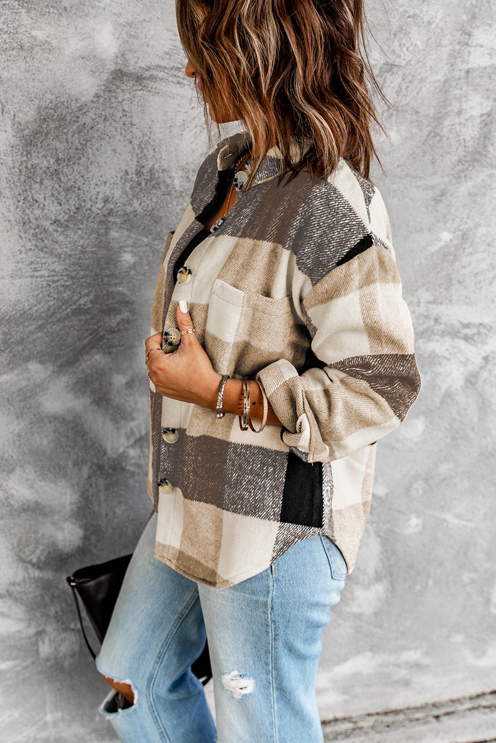 Brown haired woman wearing khaki and black plaid flannel with large button closure and pockets. left side view