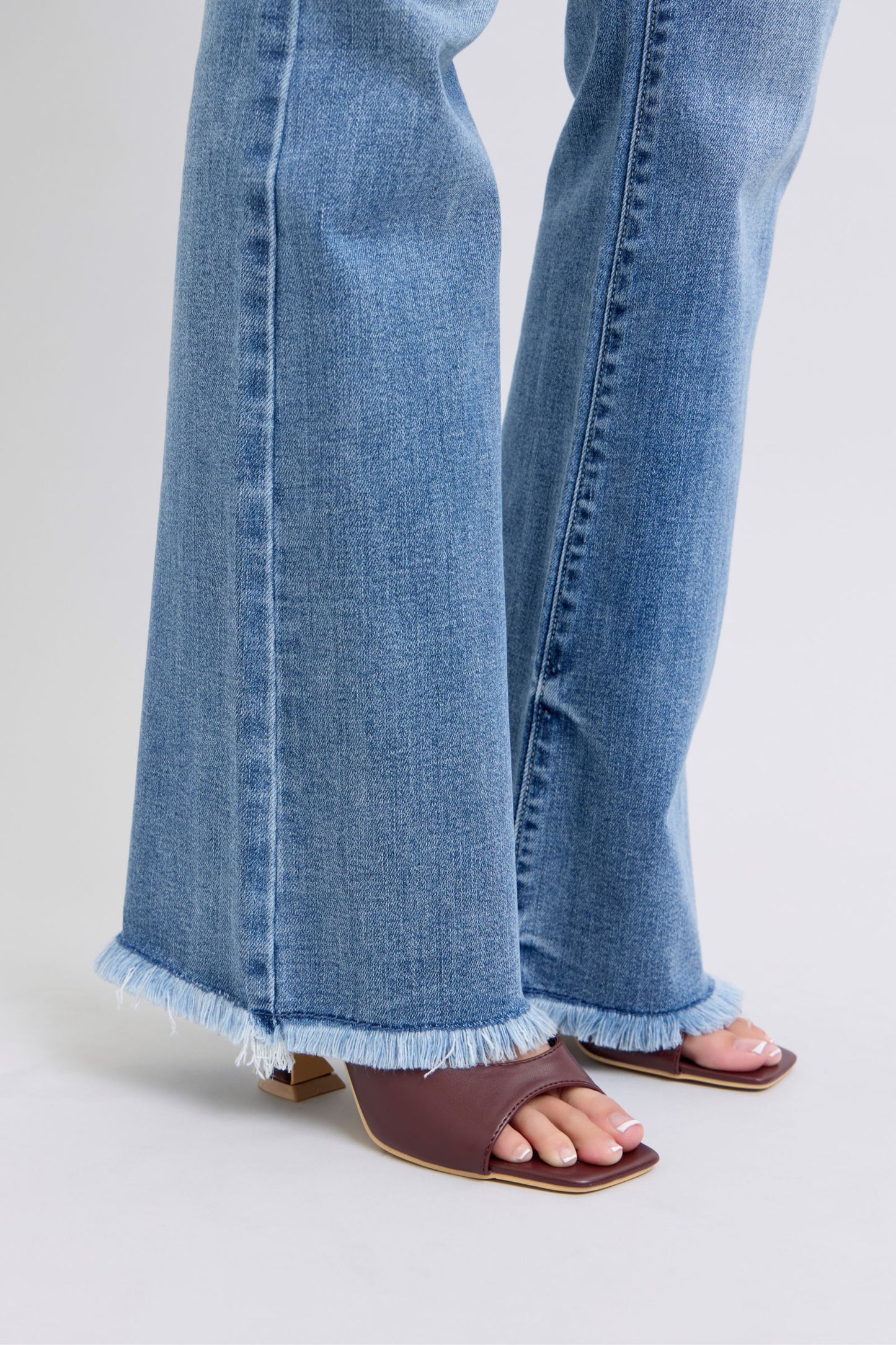 Judy Blue Raw hem high rise bootcut jeans are a trendy and stylish denim option for a fashionable look. These jeans feature a high-rise waist that sits above the natural waistline, elongating the legs and providing a flattering silhouette. The bootcut style flares out slightly from the knee down, creating a balanced and vintage-inspired look. The raw hem detail at the bottom adds a modern and edgy touch to the jeans, giving them a unique and on-trend appearance.  Close-up of hem