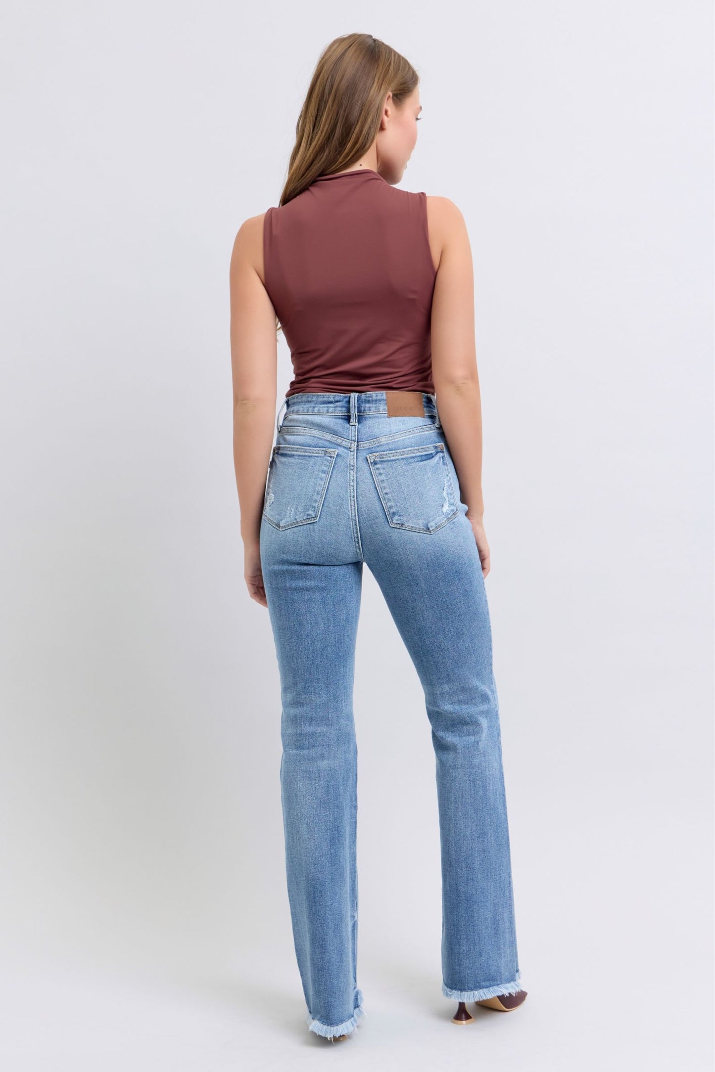 Judy Blue Raw hem high rise bootcut jeans are a trendy and stylish denim option for a fashionable look. These jeans feature a high-rise waist that sits above the natural waistline, elongating the legs and providing a flattering silhouette. The bootcut style flares out slightly from the knee down, creating a balanced and vintage-inspired look. The raw hem detail at the bottom adds a modern and edgy touch to the jeans, giving them a unique and on-trend appearance.  Back view