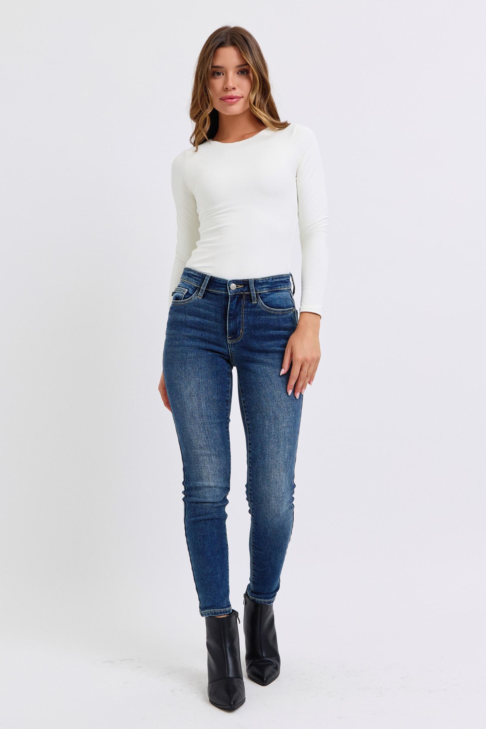 Judy Blue Mid-Rise Waist Skinny Jeans with Pockets are a versatile and essential piece for any wardrobe. With a flattering mid-rise waist and slimming skinny fit, these jeans create a sleek and stylish look. 
The addition of a thin thermal lining provides lightweight warmth, making them perfect for cooler days, while the pockets offer both functionality and casual flair. Front view
