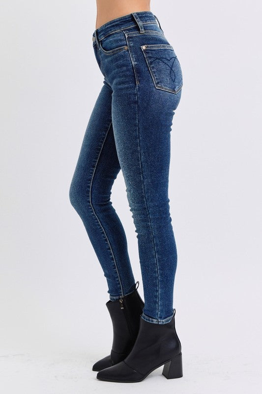 Judy Blue Mid-Rise Waist Skinny Jeans with Pockets are a versatile and essential piece for any wardrobe. With a flattering mid-rise waist and slimming skinny fit, these jeans create a sleek and stylish look. 
The addition of a thin thermal lining provides lightweight warmth, making them perfect for cooler days, while the pockets offer both functionality and casual flair. Left side view
